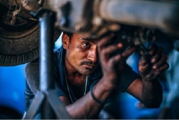 Improve your gas mileage with an AAMCO Tune-Up Mechanic tuning-up a vehicle